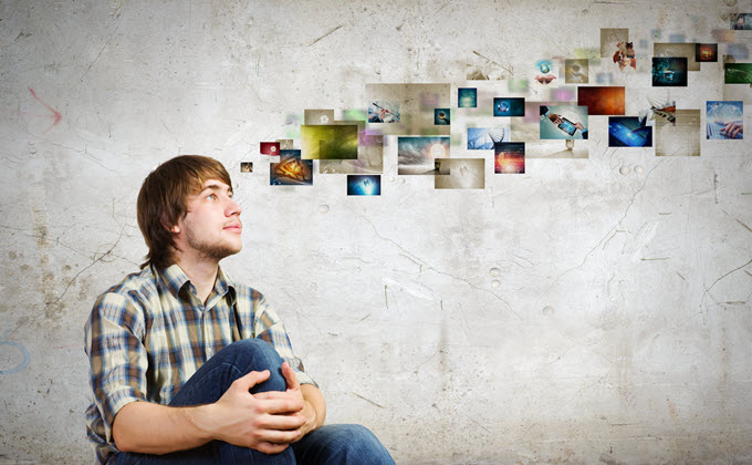 A young man looking up at a cloud of Instagram pictures.