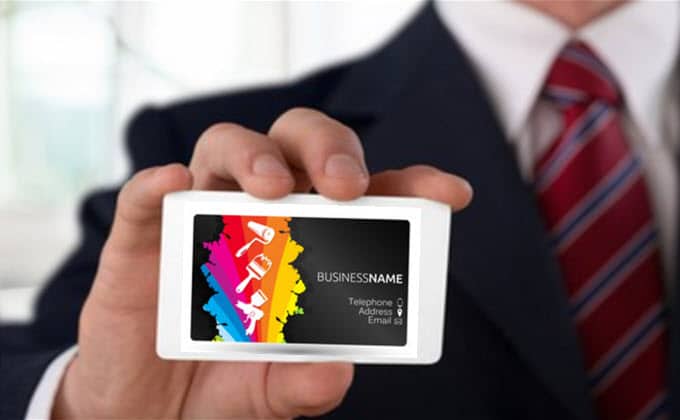 A man showcasing a business card with a vibrant design.