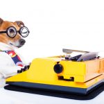 A dog, wearing glasses, is typing on a typewriter.