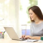 A woman is typing on her laptop at home.