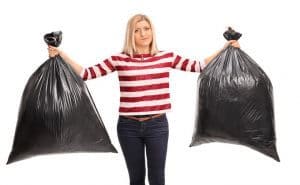 A woman holding two garbage bags on a white background.