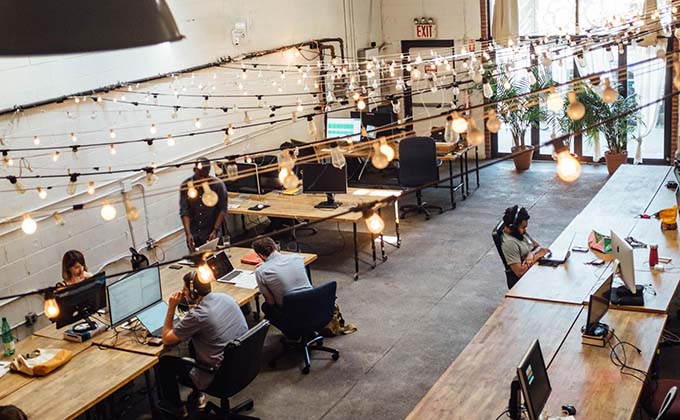 A group of people in an office with string lights hanging from the ceiling.