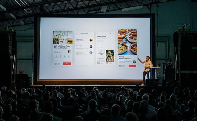 A man giving a presentation in front of a large screen.