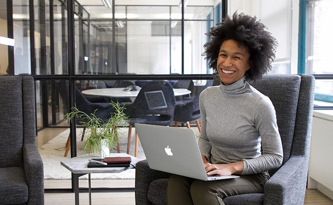 A woman sitting in an office chair with a laptop.