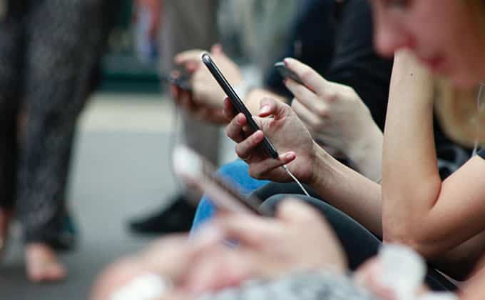 Group of people sitting in a row, focusing intently on their smartphones, embodying authentic branding.