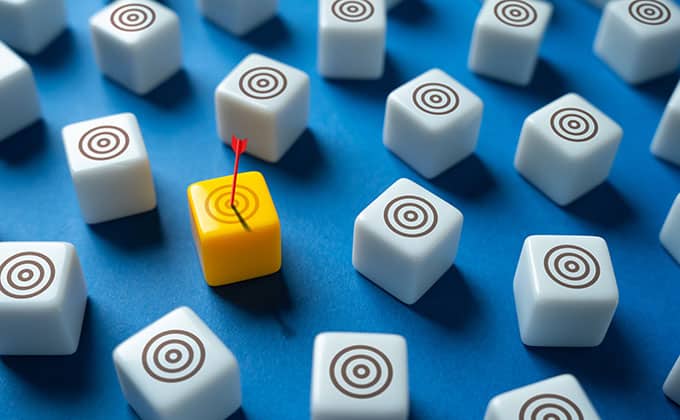 A group of white cubes with target symbols, and one yellow cube featuring a red arrow hitting its bullseye, represent how local businesses can reach nearby customers with precision—just like using geotargeted ads.
