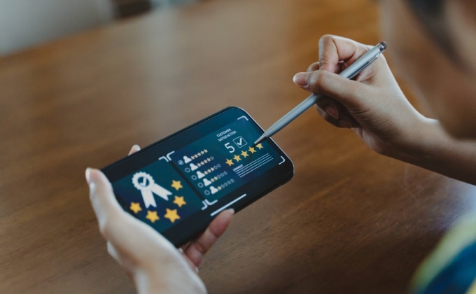 A person uses a stylus to give a five-star rating on a smartphone screen displaying a feedback form, helping boost online reputation through Google Reviews.